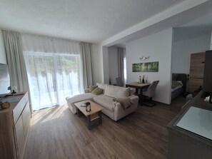 A modern living room with a sofa, coffee table, and a dining area with chairs.
