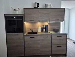 Eine moderne Küche mit Einbauofen, Kaffeemaschine und Wasserkocher auf der Arbeitsfläche.
