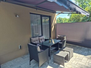 An outdoor patio with wicker furniture, a table, and a cushioned chair. - Vrbo Property (Auerbach/Vogtland)