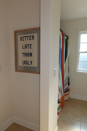 A hallway with a framed sign on the wall and a colorful striped shower curtain. - 3-bedroom house in inlet beach with private backyard (Panama City)