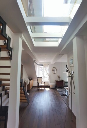 A spacious room with a skylight, wooden flooring, a chair, a small table, and a radiator. - Rooftop Terrace Loft Apartment, Home Cinema (Prague)
