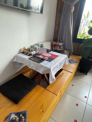 A room with a table set for a meal, a bench, and a window with curtains. - Ryokan - More than just lodging, a sensory immersion. 3 minutes from Praça da Liberdade (Liberty Square). (São Paulo)