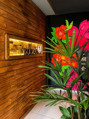 A wooden wall with a lit sign that reads 'RYOKAN' and a large floral painting with Chinese characters. - Ryokan - More than just lodging, a sensory immersion. 3 minutes from Praça da Liberdade (Liberty Square). (São Paulo)