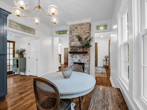 A dining area with a round table, chairs, a chandelier, a brick wall, and a staircase leading to another room. - Hendersonville Honeybee (Hendersonville)