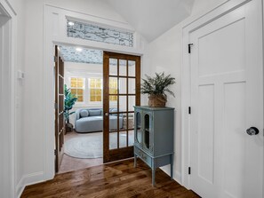 A hallway with a wooden floor, a white door, and a blue cabinet with a plant on top. - Hendersonville Honeybee (Hendersonville)