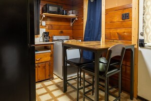 Eine kompakte Küche mit Mikrowelle, Kaffeemaschine und kleinem Kühlschrank.