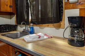 Eine Küche mit einem Spülbecken, einer Kaffeemaschine und einer Flasche Spülmittel.