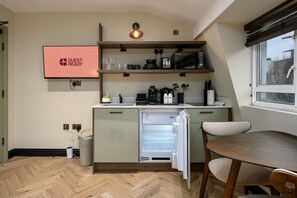 Eine kompakte Küche mit integriertem Kühlschrank, einer Kaffeemaschine und einem Schild mit der Aufschrift 'GUEST READY'.