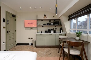 Ein kompaktes Hotelzimmer mit Küchenzeile, Essbereich und einem Bett.