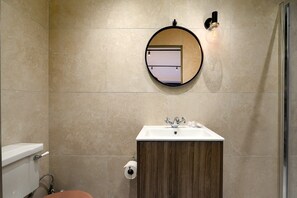 Ein Badezimmer mit rundem Spiegel, Waschbecken und Toilette.