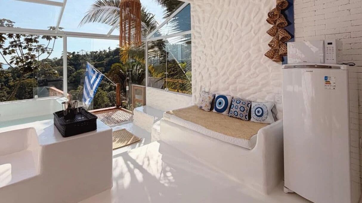 Quarto moderno com sofá branco, uma mesa pequena e um frigorífico.