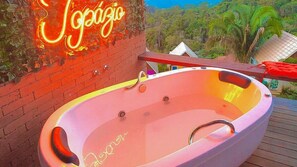 A hot tub with a neon sign above it, surrounded by a wooden deck and a view of a lush landscape. - SÍTIO EMANOEL (Domingos Martins)