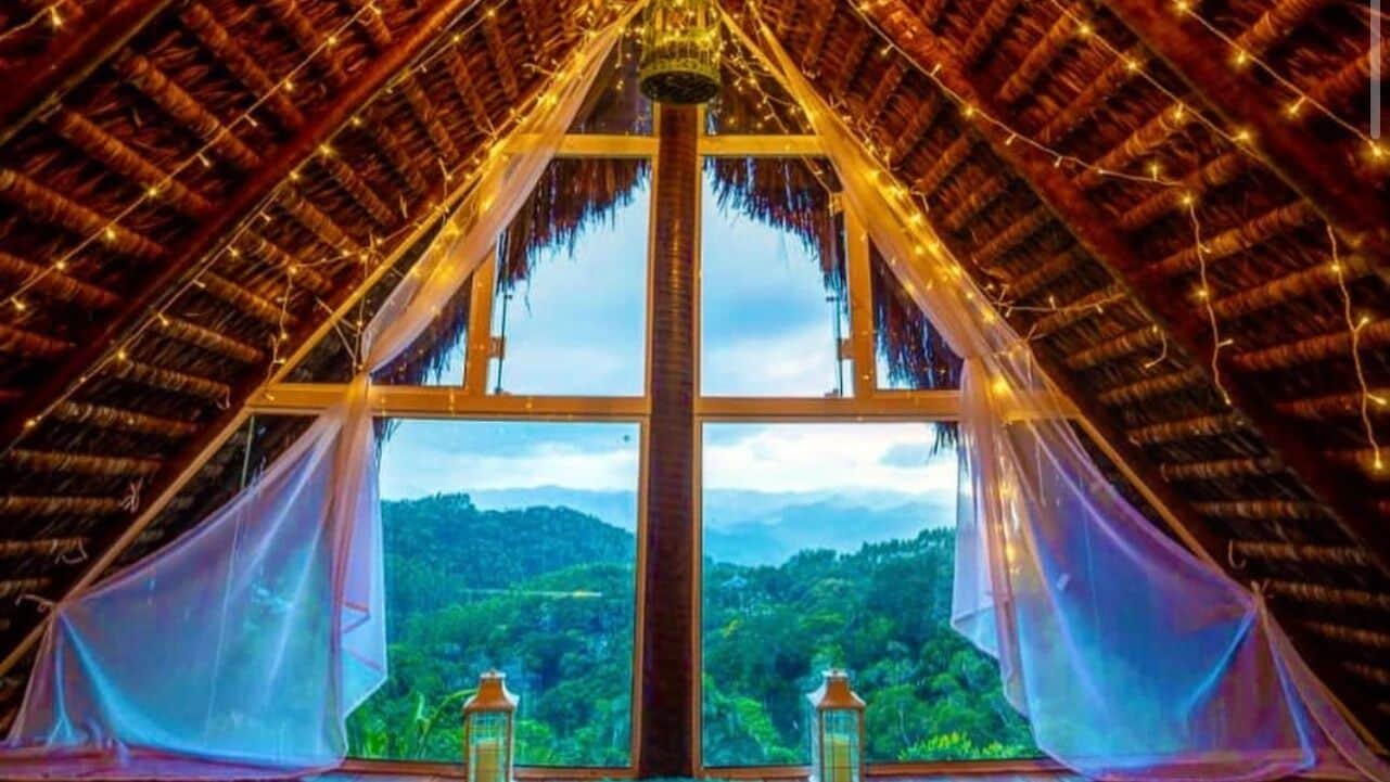 Una habitación con un ventanal grande, techo de madera y vistas a un paisaje verde.
