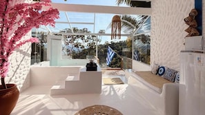 Un interior moderno con pared de vidrio, escalera blanca y vistas al exterior.