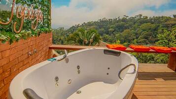 Uma banheira de hidromassagem em um deck de madeira com vista para uma floresta exuberante.
