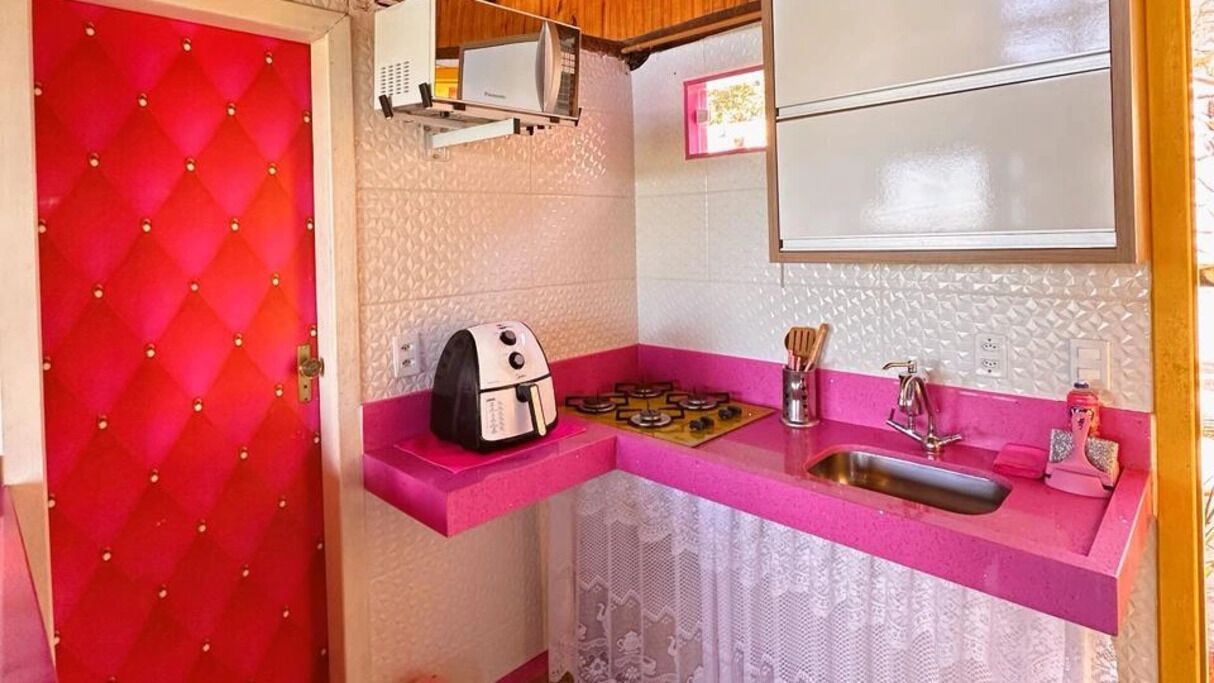 Cocina compacta con una puerta roja, un tostador, un lavamanos y una ventana sobre la encimera.