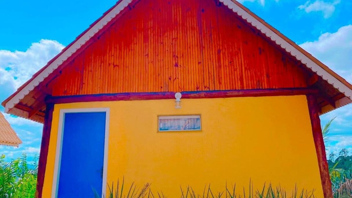 Um pequeno edifício térreo com telhado vermelho e paredes amarelas.