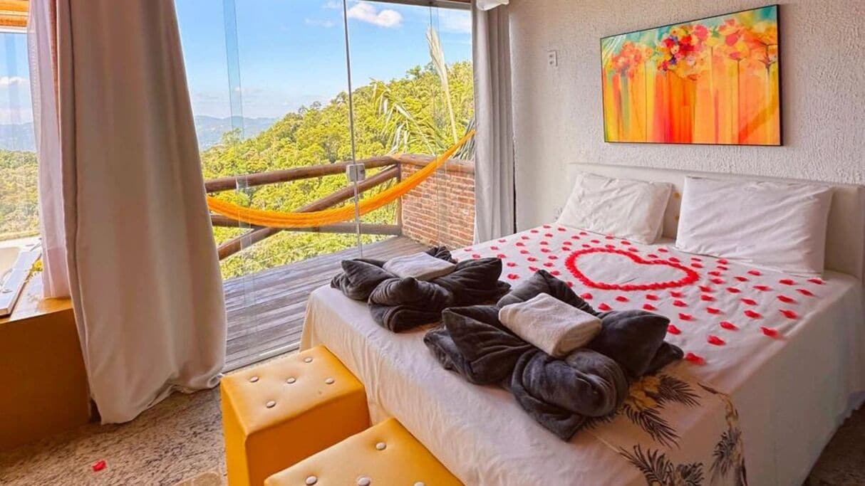 A bedroom with a bed, a hammock, and a view of the outdoors.