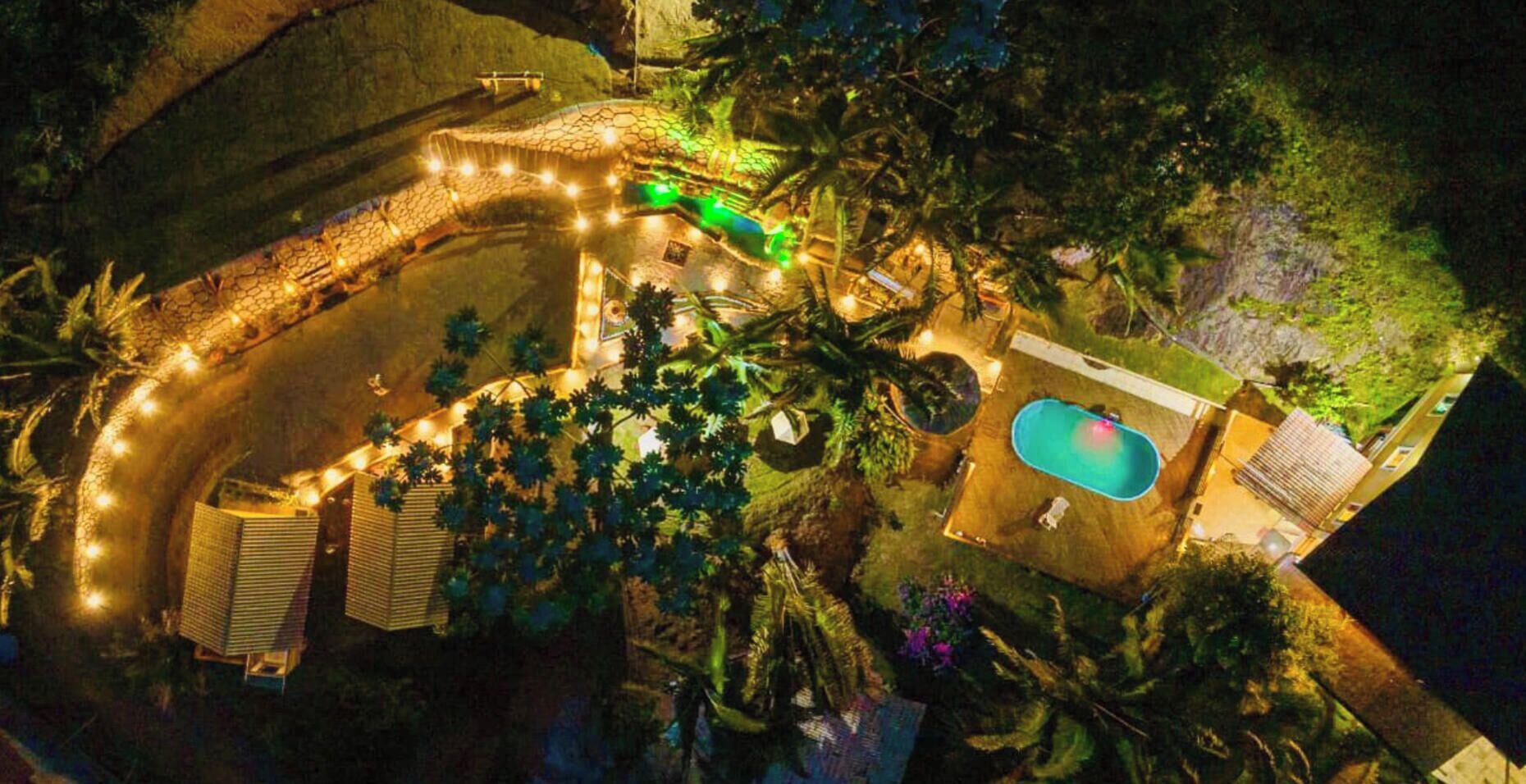 Eine Luftaufnahme eines Anwesens mit Schwimmbad, überdachter Terrasse und einem angelegten Garten.