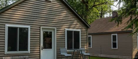A two-story house with a front porch, a door, and two windows.