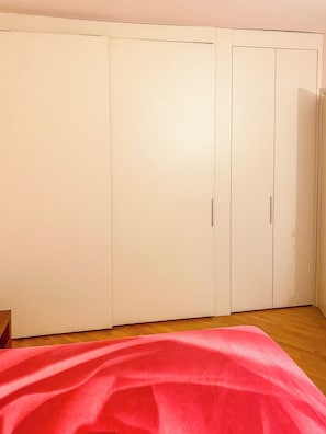Une chambre avec un lit, une armoire et un plancher en bois.