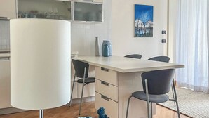 Una cocina moderna con armarios blancos, un comedor con mesa y sillas, y un amplio ventanal con cortinas.