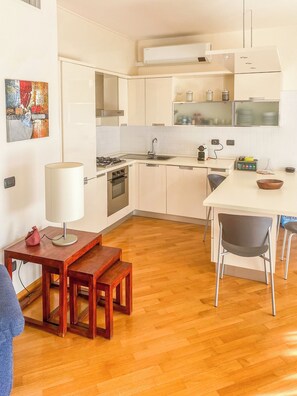 Une cuisine moderne avec des meubles blancs, une table à manger en bois et un banc.