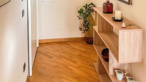 Un pasillo con suelo de madera, una puerta blanca y una consola de madera decorada con adornos.