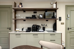 A compact kitchen with a microwave, coffee maker, and utensils on the countertop. - GuestReady -Top floor retreat in Euston (London)