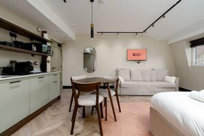 A modern hotel room with a dining area, a sofa, a bed, and a television displaying 'GUEST READY'. - GuestReady -Top floor retreat in Euston (London)