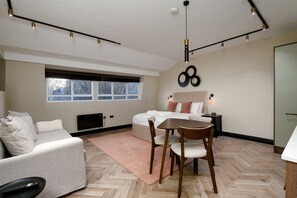 A modern hotel room with a bed, a desk, a chair, a TV, and a large window. - GuestReady -Top floor retreat in Euston (London)