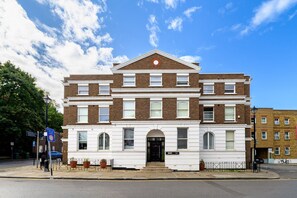 A two-story building with a symmetrical facade, large windows, and a central entrance with steps. - GuestReady - Studio by the Maritime Museum (London)