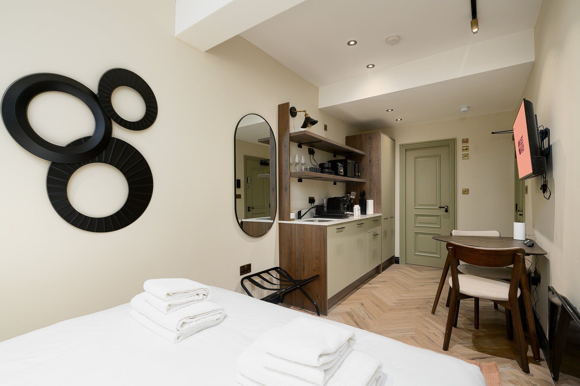 Une chambre d’hôtel comprenant un lit, une chaise, un bureau, un miroir et une kitchenette.
