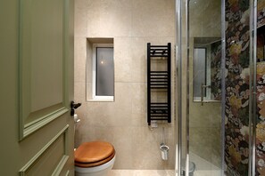 Ein Badezimmer mit Toilette, einem Fenster, einem Handtuchhalter und einer Duschkabine.