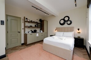 A bedroom with a bed, bedside tables, a wardrobe, and a wall-mounted light fixture. - GuestReady - Sleek studio in Euston (London)