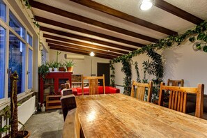 Spiseområde med et træbord, røde stole og krukker med planter.