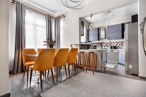 A modern kitchen with a dining area, featuring a bar stool setup, a dining table, and a refrigerator. - Serene 3BR Spacious Apartment with Indoor Terrace & Bosphorus Views (istanbul)