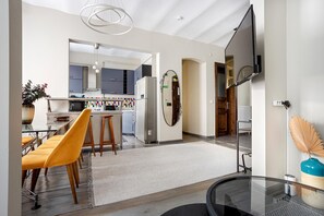 A modern kitchen with a dining area, a large mirror, and a TV mounted on the wall. - Serene 3BR Spacious Apartment with Indoor Terrace & Bosphorus Views (istanbul)
