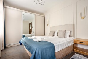 A hotel room with a large bed, a wooden nightstand, a mirror, and a sliding door leading to a bathroom. - Serene 3BR Spacious Apartment with Indoor Terrace & Bosphorus Views (istanbul)