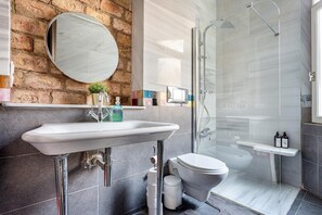 Et moderne badeværelse med en marmorvask, toilet og brusekabine med glasvægge.
