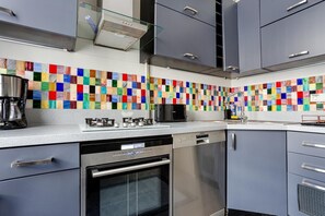 A modern kitchen with grey cabinets, a colorful backsplash, a coffee maker, a microwave, and a dishwasher. - Serene 3BR Spacious Apartment with Indoor Terrace & Bosphorus Views (istanbul)