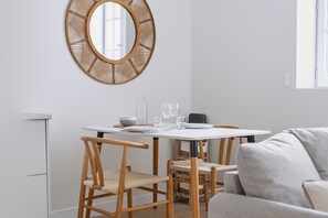 A dining area with a round mirror, white table, and wicker chairs. - Free parking • Downtown on foot • Air Conditioning (Albi)