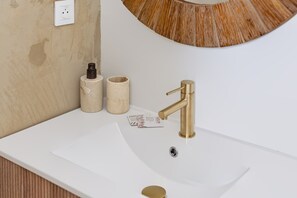 A bathroom sink with a gold faucet, a white wall, and a wooden vanity. - Free parking • Downtown on foot • Air Conditioning (Albi)