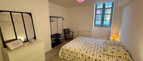 A bedroom with a bed, a chair, a dresser, a hanging chair, a window, and a ceiling light.