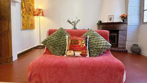Una habitación con un sofá tapizado rojo, una chimenea y un cuadro en la pared.