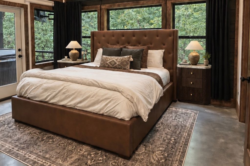 A bedroom with a large bed, two bedside tables, and a view of greenery outside.
