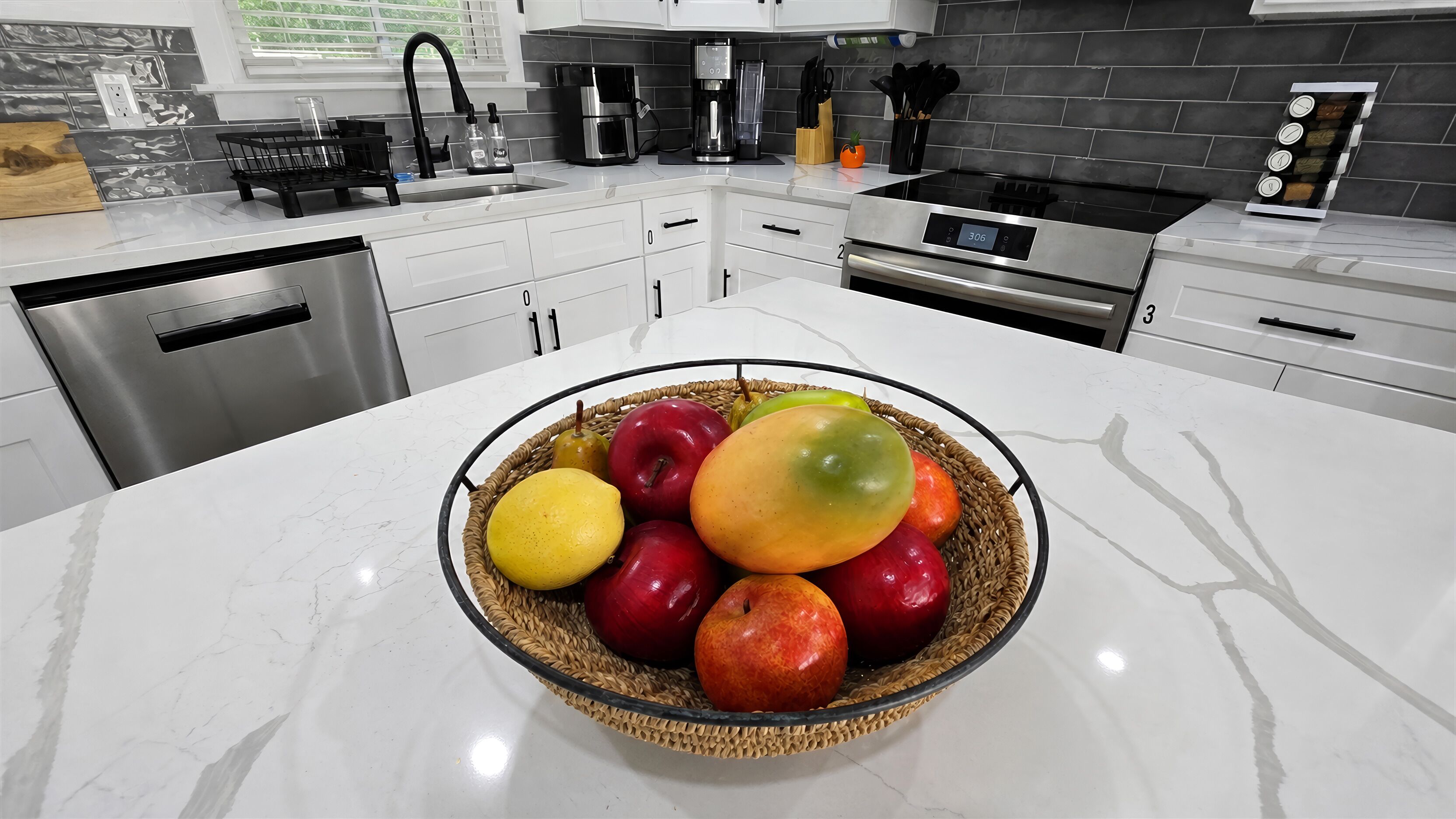 Une cuisine équipée d’un lave-vaisselle en acier inoxydable, d’une machine à café et d’un panier à fruits posé sur le plan de travail.