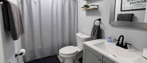 A bathroom with a toilet, sink, and shower curtain.