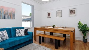 Ein modernes Wohnzimmer mit einem blauen Sofa, einem Holzesstisch und einer Topfpflanze.