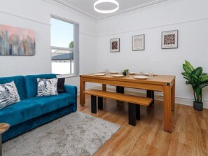 Ein modernes Wohnzimmer mit einem blauen Sofa, einem Holzesstisch und einer Topfpflanze.